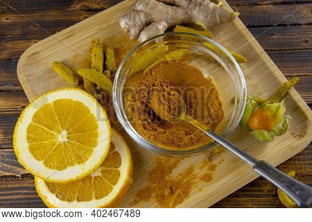 Urmeric Powder In A Glass Bowl And Orange Slices On A Light Wooden Tray.