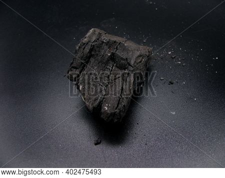 A Piece Of Brown Coal On A Dark Background. A Mineral Resource.