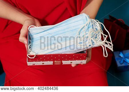 Female Hands Holding Red Gift Box Full Of Medical Masks.