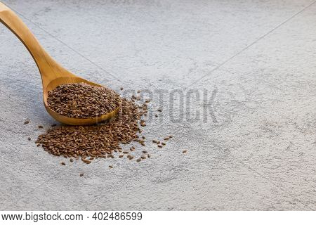 Flax Seeds In A Wooden Spoon On A Gray Concrete Background, A Natural Source Of Omega-3, Vitamins B