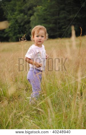 Scared cute little girl lost on the meadow looking around for help.