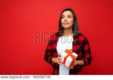 Photo Shot Of Pretty Positive Young Brunette Woman Isolated Over Red Background Wall Wearing White C