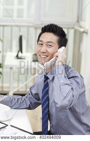 Businessman Using A Laptop And Phono In An Office High Quality Photo