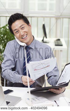 Businessman Using A Laptop And Phono In An Office High Quality Photo