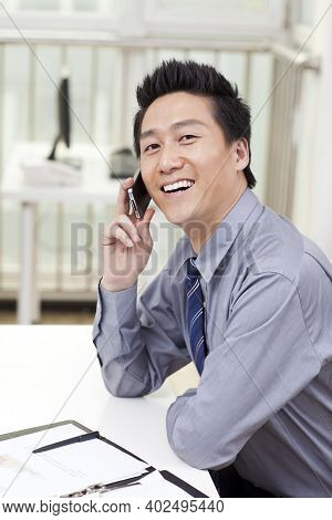 Businessman Using A Laptop And Phono In An Office High Quality Photo