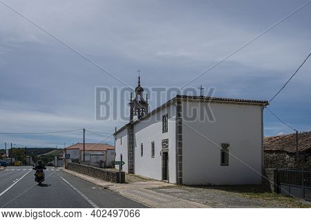 Boente, Spain, July 2020 - A Motorbike Riding Past A Church In The Village Of Boente, Spain