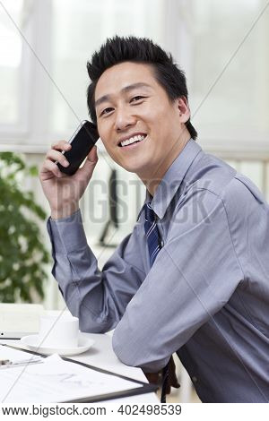 Businessman Using A Laptop And Phono In An Office High Quality Photo