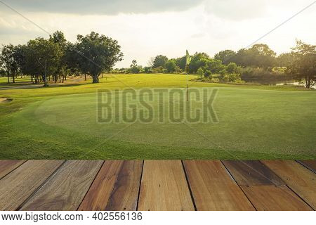 Wooden Floor And Golf Course Background. Fresh Spring Green Golf Course With Wood Floor. Beauty Natu