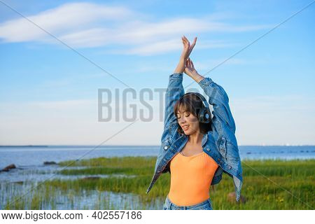 Happy Young Woman Dancing In Headphones On The Shore Of The Bay Sun Sunny Spring Day