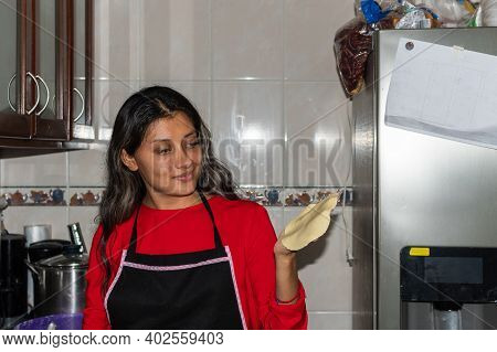 Young Woman Wearing A Red Shirt Preparing Some Tortillas With Her Hands On Her Kitchen House