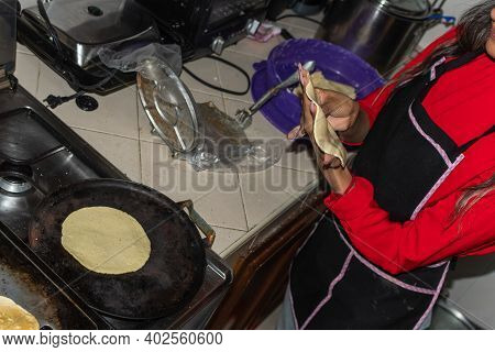 Young Woman Wearing A Red Shirt Preparing Some Tortillas With Her Hands On Her Kitchen House