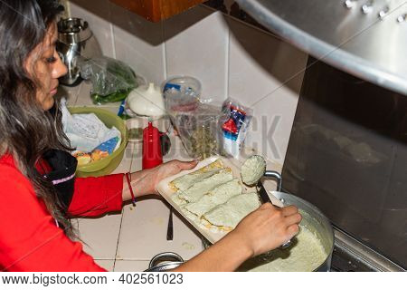 Young Woman Wearing A Red Shirt Preparing Some Tortillas With Her Hands On Her Kitchen House