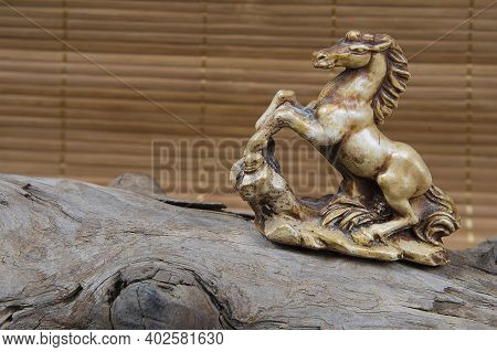 Closeup Of Japanese Netsuke Figure On Wooden And Bamboo Background. Statue Horse Mascot