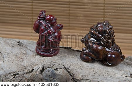 Closeup Of Japanese Netsuke Figure On Wooden And Bamboo Background. Statue Japanese God And Lion Mas
