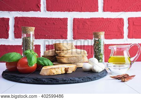 White Bread Croutons With Mozzarella, Basil, Spices And Tomato On A Stone Stand On A Brick Backgroun