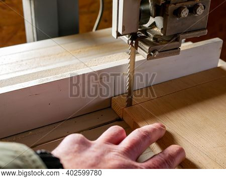 Carpenter With A Missing Finger Cutting A Piece Of Plywood At The Bandsaw, Focus On The Sharp Blade.