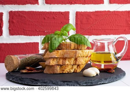 White Bread Croutons With Mozzarella, Basil And Rapeseed Oil In A Jug On A Stone Stand On A Brick Ba