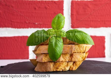 White Bread Croutons With Mozzarella And Basil On A Stone Stand On A Brick Background