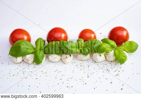 Mozzarella With Whole Tomatoes And Basil Sprinkled With Spices And Dressings On A White Table On A  