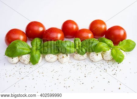 Mozzarella With Whole Tomatoes And Basil Laid Out In A Row And Sprinkled With Spices And Dressings O
