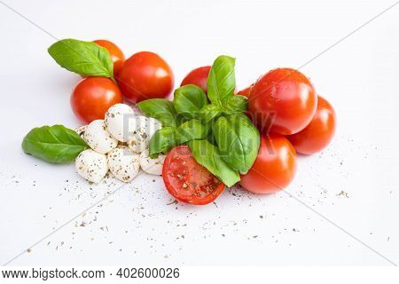 Fresh Mozzarella With Tomatoes And Green Basil Sprinkled With Spices And Dressings On A White Table 