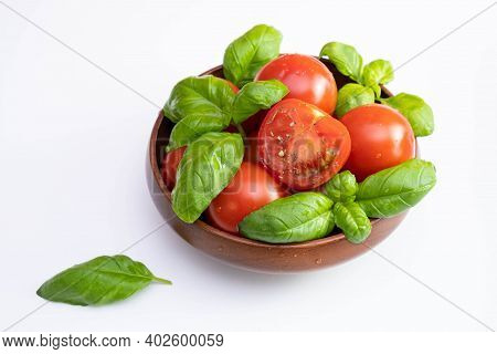 Fresh Tomatoes And Green Basil In A Wooden Cup On A White Table And White Plate