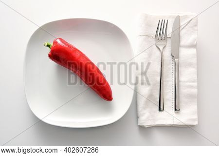 Raw Red Pointed Sweet Pepper On A White Plate, Cutlery And Napkin Beside On A Bright Background, Hea