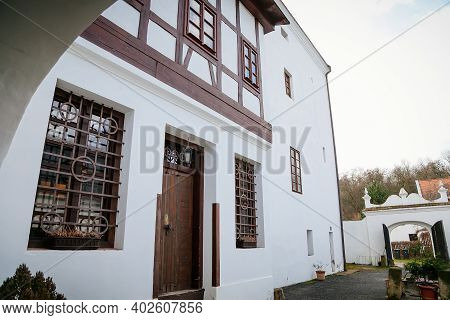 Chateau Courtyard, Detail Of Half Timbered White Walls With Some Doors And Windows Of Romantic Medie