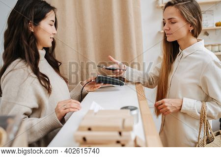 Comfortable Female Customer Making A Purchaise, Paying With Her Phone.