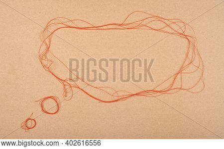 Speech Or Think Bubble Made Of Thread, Red Rope. Thematical Copy Space On Cardboard Textured Backgro