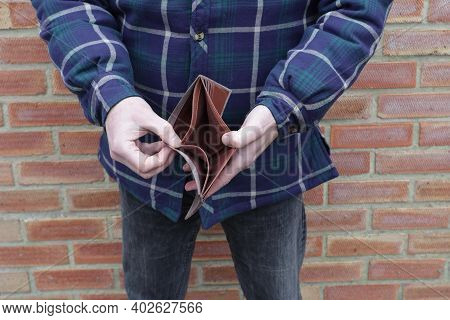 Man With No Money Showing Empty Wallet With Brick Wall Behind