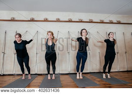 Lyengar Female Group Of Yogi Practicing Calisthenics Exercise In Yoga Studio Hanging On A Wall With 