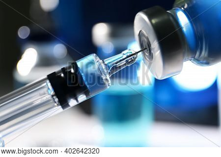 Filling Syringe With Vaccine From Vial On Blurred Background, Closeup