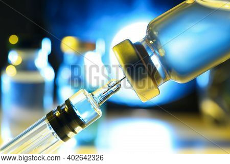 Filling Syringe With Vaccine From Vial On Blurred Background, Closeup