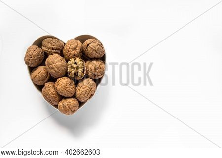 Whole Walnuts And One Cracked Broken Heart In A White Heart-shaped Bowl On A White Background. Top V