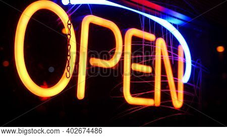 Open Neon Sign Glowing In The Dark. Vivid Retro Styled Text At Entrance On Glass Window. Colorful El