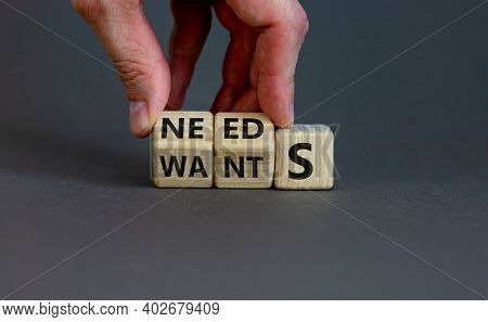 Wants Or Needs Symbol. Hand Turns Cubes And Changes The Word 'wants' To 'needs'. Beautiful Grey Back