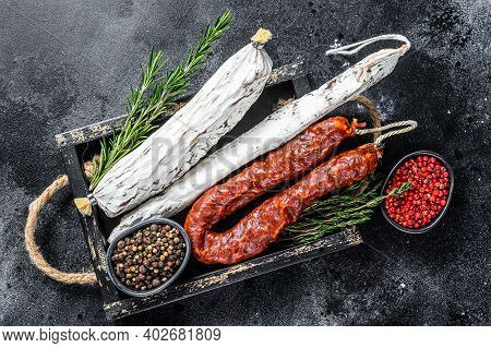 Spanish Dry Cured Sausages Salami, Fuet And Chorizo In A Wooden Tray. Black Background. Top View