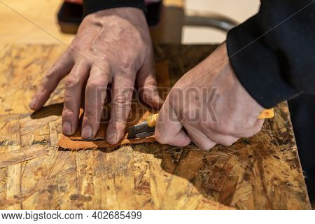 Moments From A Native Drum Workshop. Close Up Of Mans Hand Cutting A Piece Of Leather With A Carpent