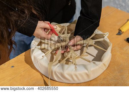 Snapshots From A Native Drum Workshop. Close Up Of Young Womans Hands Cutting The Ends Of A Leather 