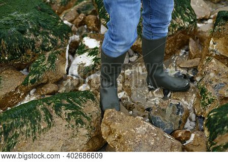 Rubber Boots On Stones With Seaweed In Ocean