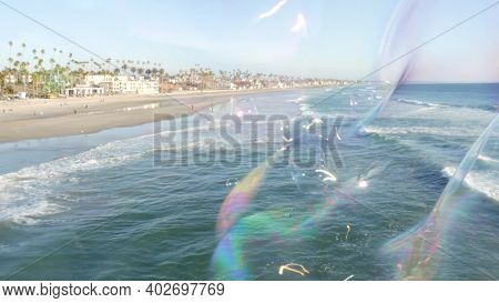 Blowing Soap Bubbles On Ocean Pier In California, Blurred Summertime Background. Creative Romantic M