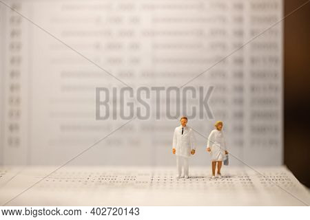 Healthcare, Business And Financial Concept. Docter And Nurse Miniature Figure Standing On Bank Passb