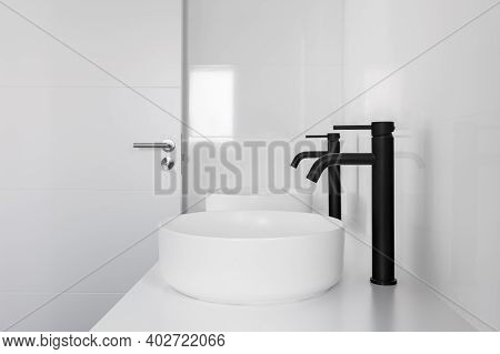 White Tiled Bathroom With Two Wash Basins And Black Faucets