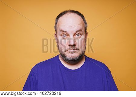 Portrait Of Mid Adult Man With Dumbfounded Look On His Face Against Orange Color Studio Background -