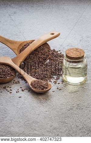 A Jar Of Linseed Oil Flax Seeds In A Wooden Spoon On A Concrete Background, A Dietary Cereal Ingredi