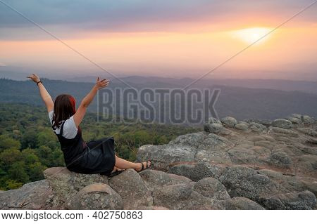 Achievement Concept. Asian Woman Raising Hands Sitting On Nodule Rock Field Called Lan Hin Pum Enjoy