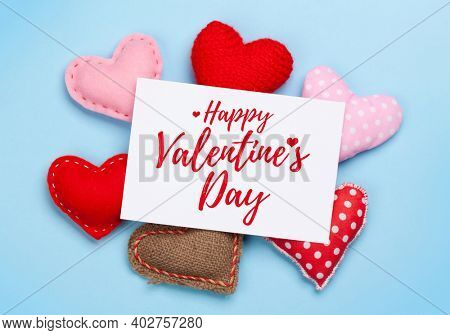 Valentines day greeting card over heart shaped decor on blue background. Top view flat lay