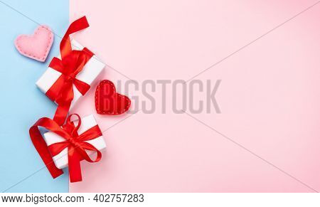 Valentines day greeting card template. Gift boxes and heart shaped decor over blue and pink background. Top view flat lay with copy space