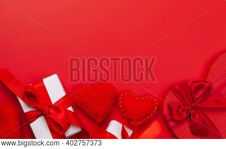 Valentines day greeting card template. Gift boxes and heart shaped decor over red background. Top view flat lay with copy space